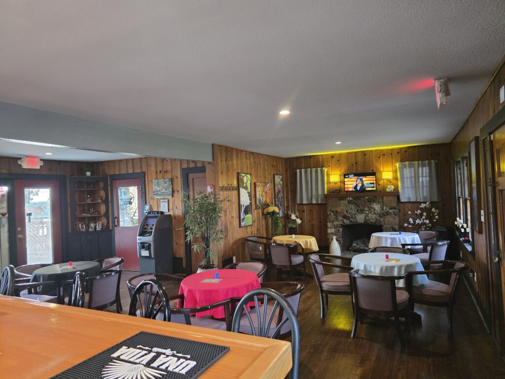 Dining room at Eagles Nest Lounge with bar seating and tables by the stone fireplace