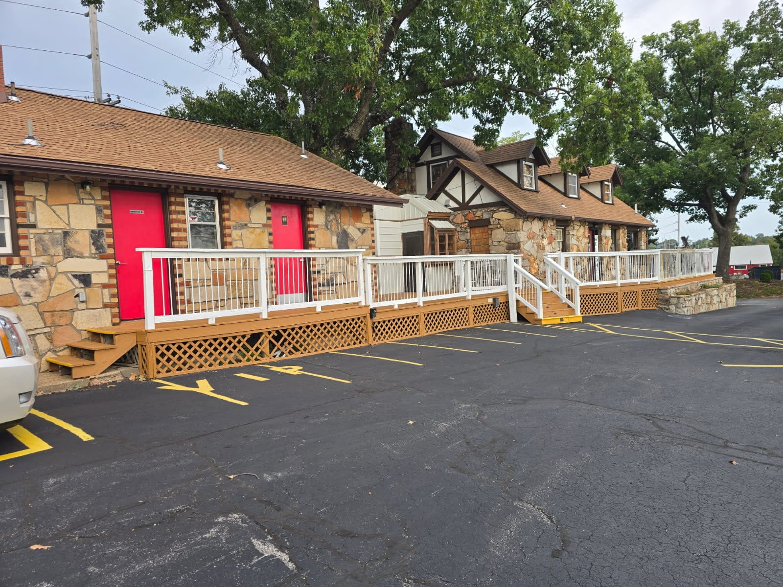Eagles Nest Motel exterior with stone rooms, red doors and a wraparound wooden deck in Lake Ozark